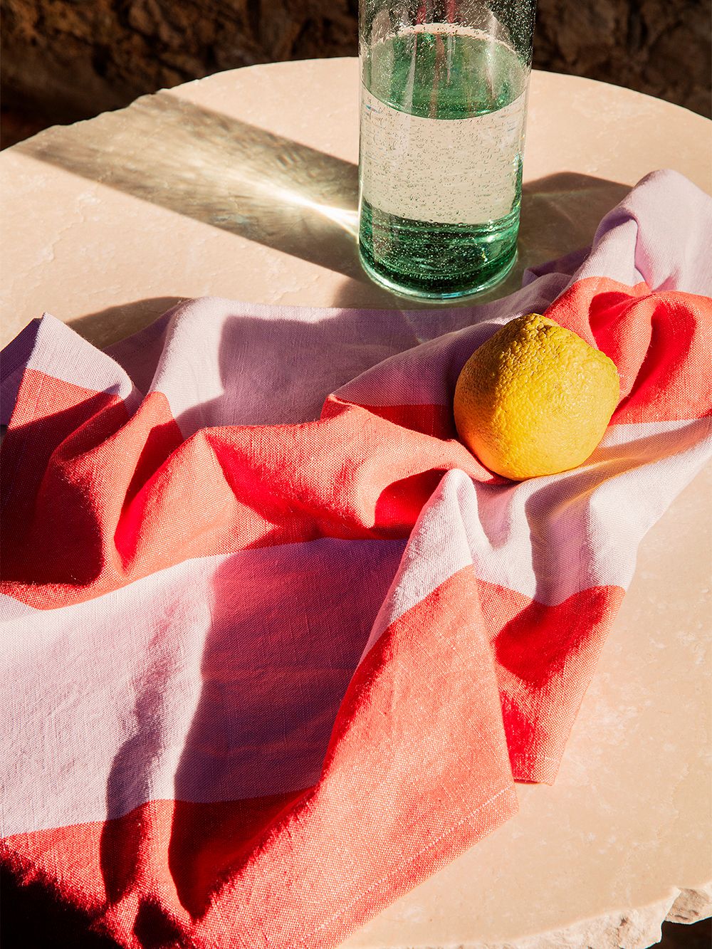 An image of ferm LIVING's Hale kitchen towel in red and lilac, on a table, as part of the kitchen decor.