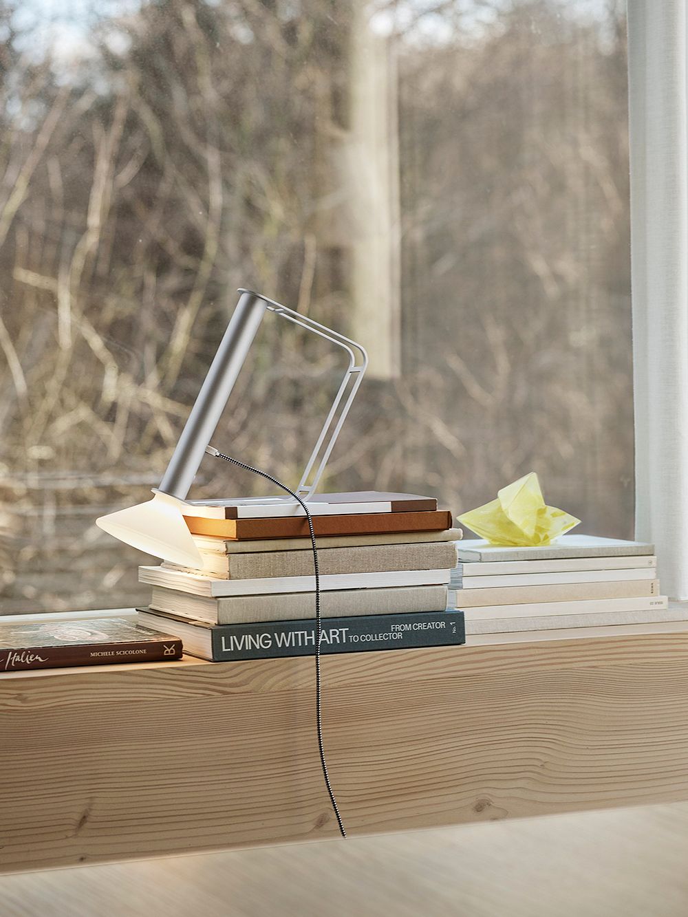 Muuto's Piton lamp placed on a stack of books.