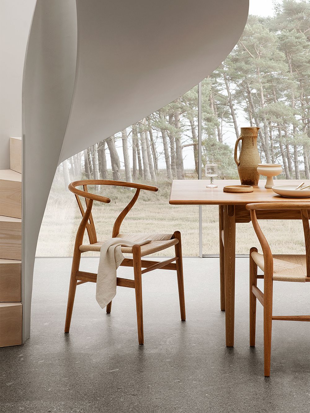 An image featuring Carl Hansen & Søn's CH24 or Wishbone chair as part of the dining room decor.