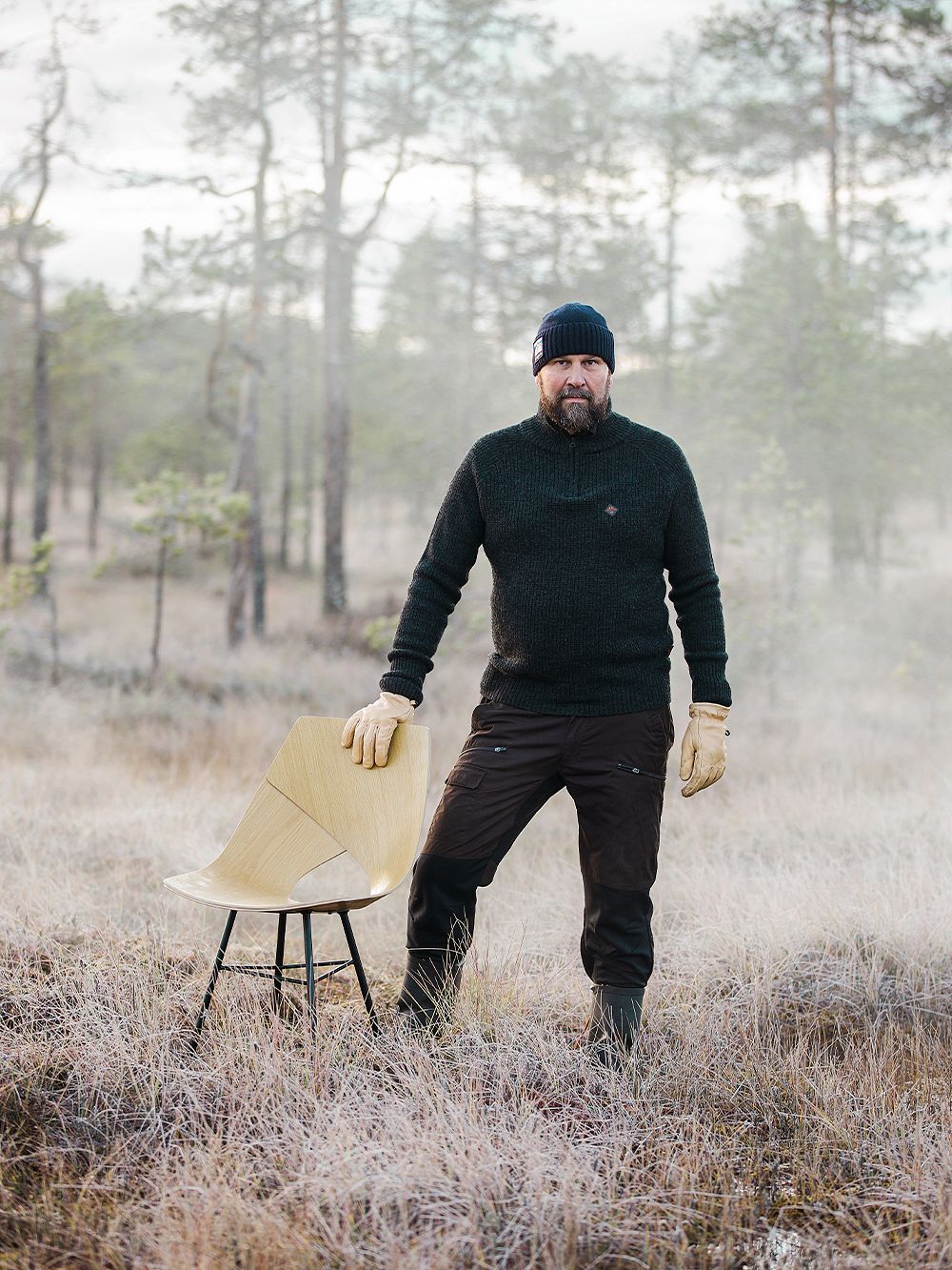 Muotoilija Tapio Anttila seisoo metsässä usvan keskellä pidellen kiinni viereen asetetun Limi-tuolin selkänojasta.