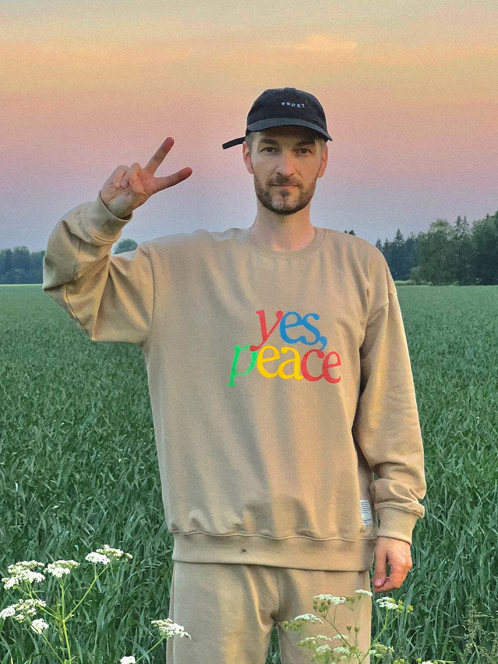 Kuva, jossa Tomi Leppänen päällään vaalea collegepaita, jossa lukee värikkäin kirjaimin "yes, peace".