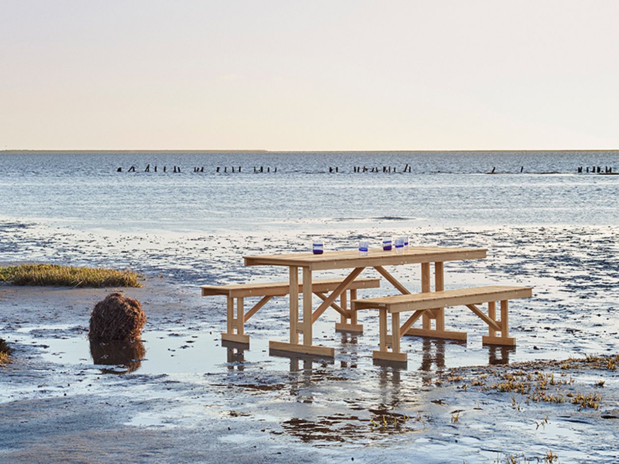 An image of Carl Hansen & Søns BM1771 table and BM1871 benches on the beach.
