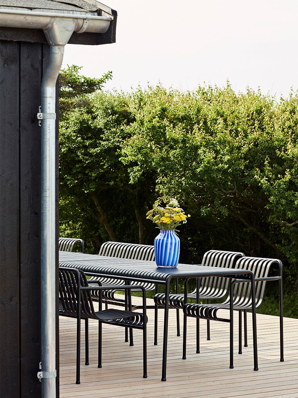An image of HAY's Palissade outdoor dining table and Palissade chairs on a summer house terrace, as part of the summer home decor.