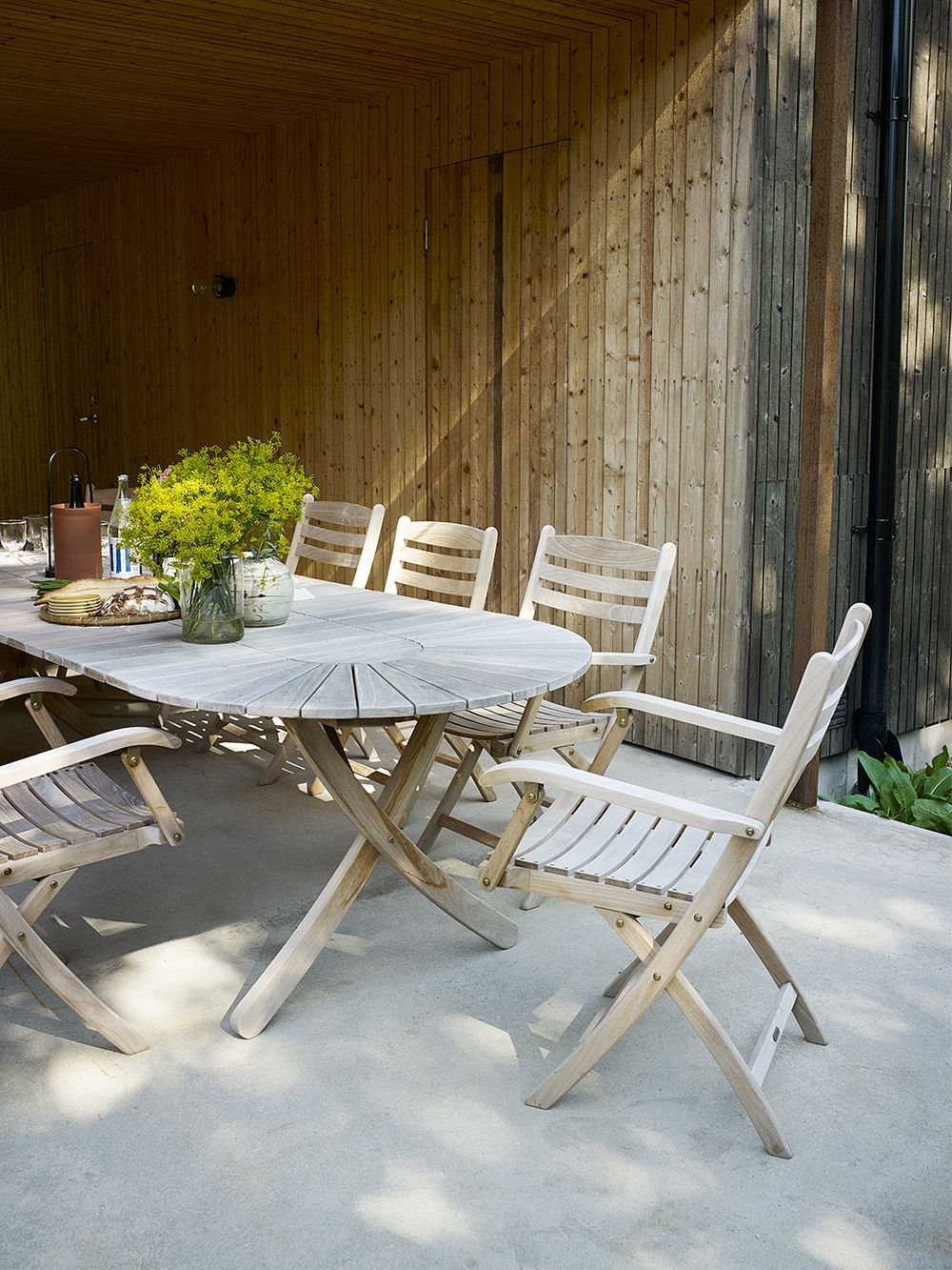 Kuva, jossa Skagerakin Selandia-kokoelman pöytä ja tuolit kesämökin pihalla, osana kesämökin sisustusta.