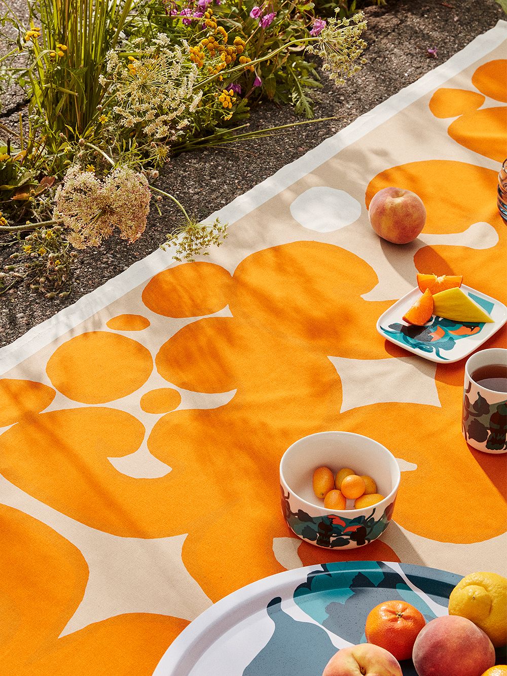 An image of Marimekko's Keidas fabric placed on the ground, with Pepe tableware on top of it.