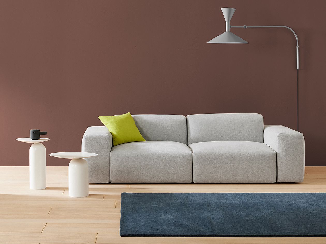 Basta's Cubi sofa in grey and two white Disco tables, all placed in a living room.