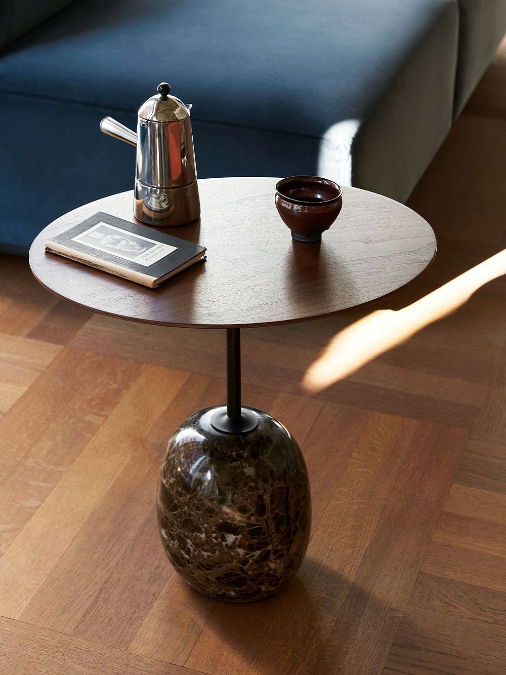 &Tradition's Lato coffee table with a walnut table top and black emperador marble base, placed in a living room.