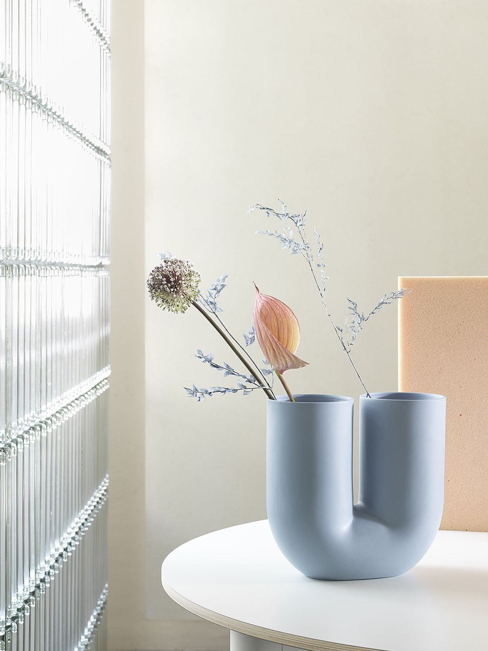 Muuto's light blue Kink vase filled with a few flowers.