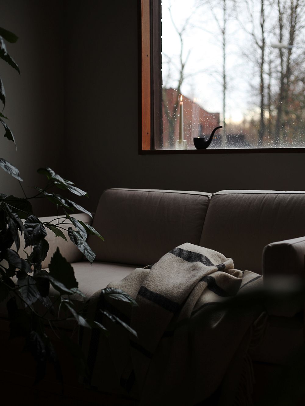 Kuva sohvasta ja kynttilänjaloista ikkunalaudalla
