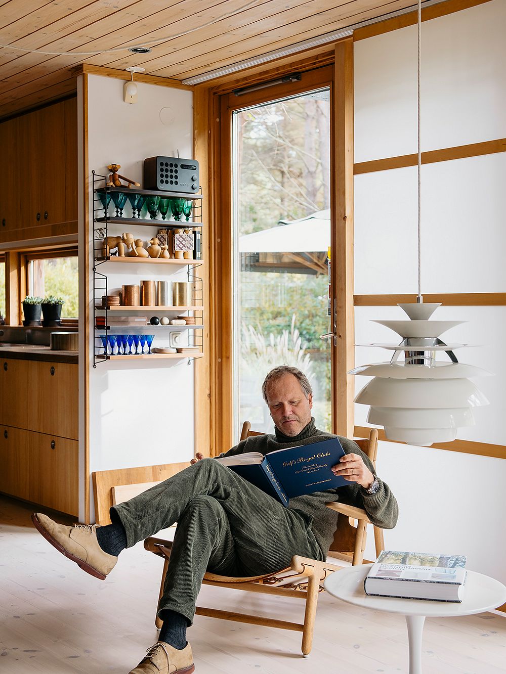 Peter Erlandsson istuu nojatuolissa ja selaa kirjaa