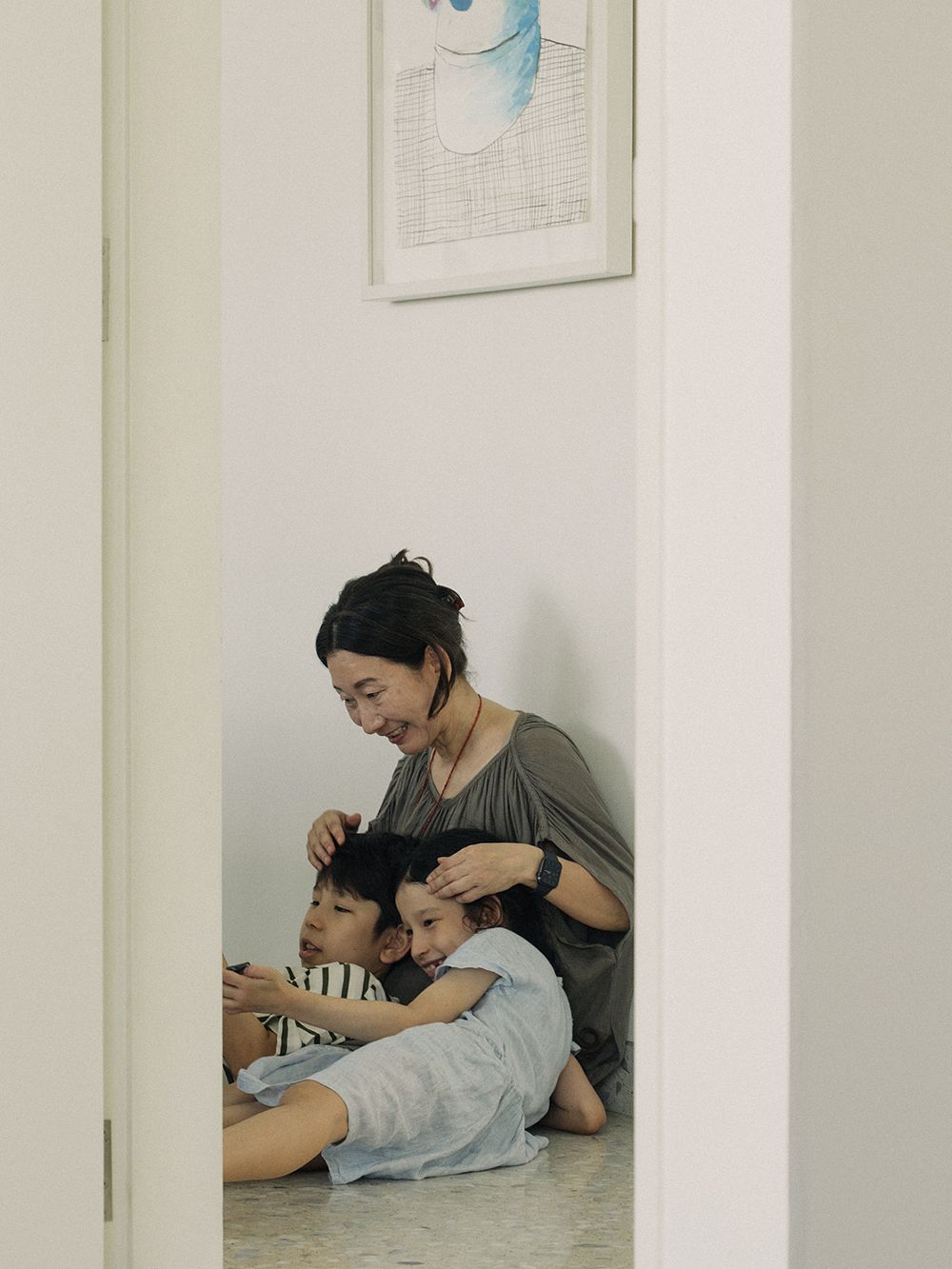 Äiti ja lapset istumassa lattialla