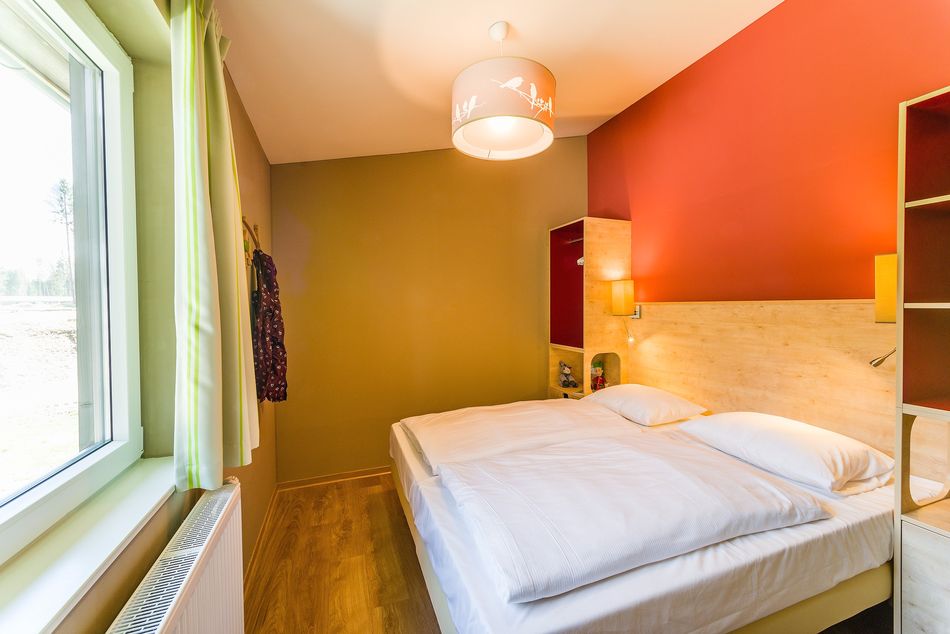 Die Rot- und Grüntone aus dem Wohnbereich finden sich im Schlafzimmer wieder.