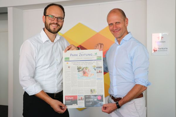 Tobias Pearman (links, Geschäftsführer Schwäbische Zeitung Leutkirch) und Christoph Muth (General Manager Center Parcs Park Allgäu) mit einem ersten Entwurf der Park Zeitung im Sommer 2018. Foto: Simon Nill