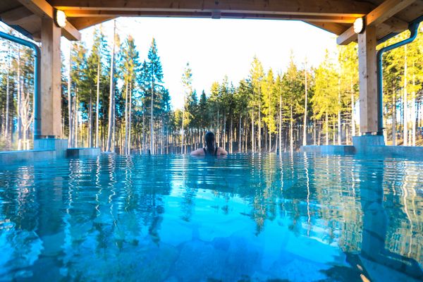 Femme profitant d’un bain chaud en pleine forêt, spa extérieur dans un cadre naturel et apaisant pour couples