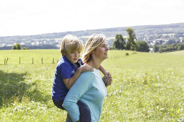 Une mère portant son fils sur le dos lors d'une promenade à la campagne.