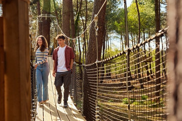 Un couple marche sur un pont suspendu au milieu d'une forêt