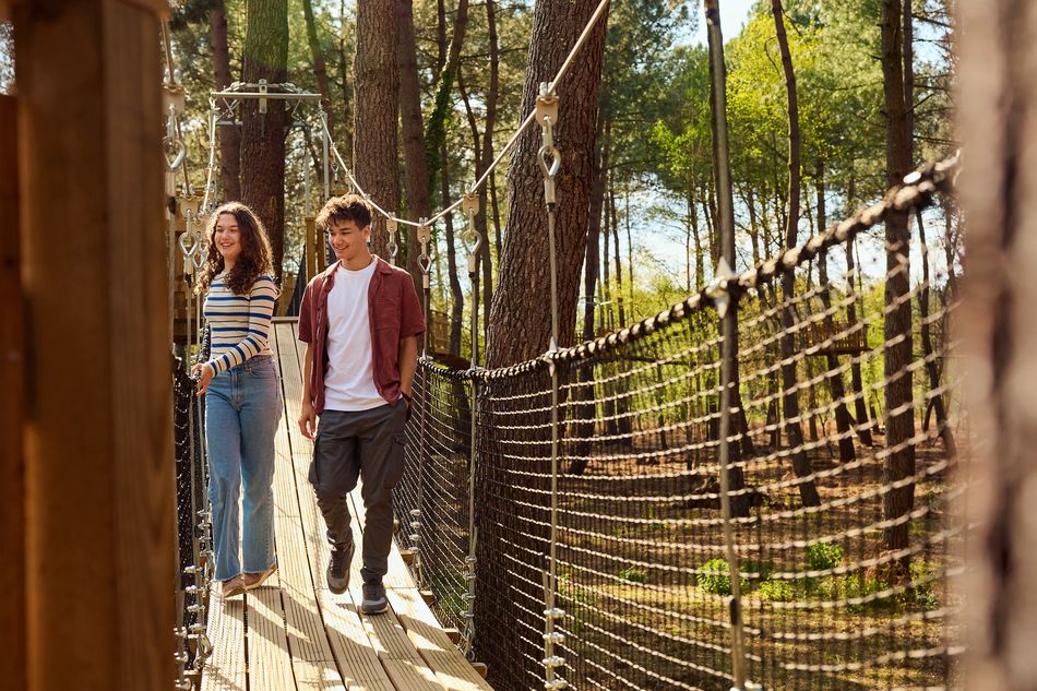 Un couple marche sur un pont suspendu au milieu d'une forêt