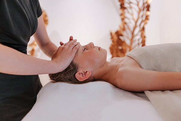 Une femme allongée sur une table de massage reçoit un soin relaxant au visage dans un spa.