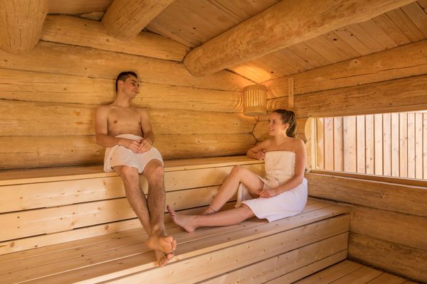 Couple se relaxant dans un sauna en bois chaleureux, expérience bien-être lors d’un week-end en amoureux