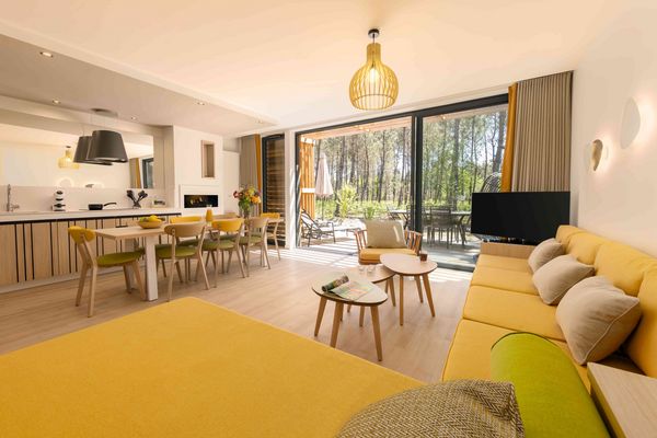 Intérieur lumineux d’un cottage Center Parcs avec salon moderne, cuisine équipée et terrasse donnant sur la forêt, idéal pour des vacances en famille ou en couple