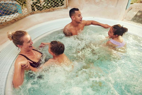 Famille souriante profitant d’un moment de détente dans un jacuzzi à Center Parcs, vacances bien-être avec enfants en juillet