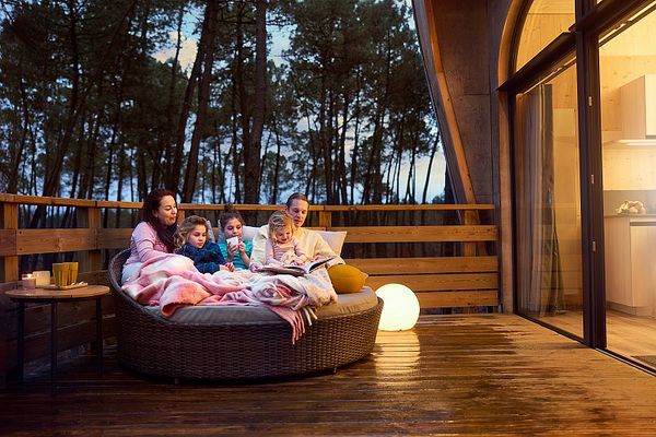 Famille dans un canapé d'extérieur dans le balcon de leur cottage