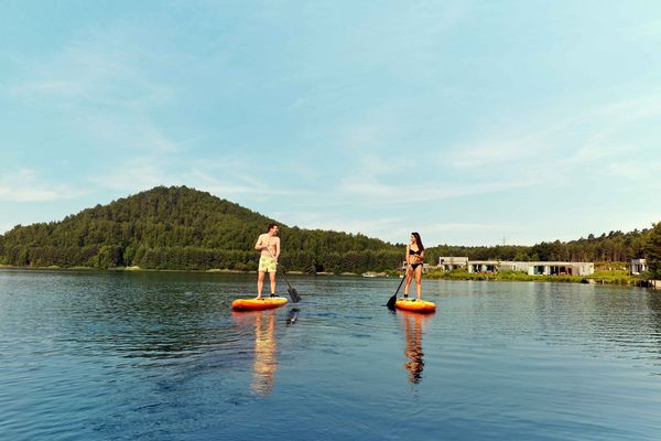 Couple faisant du paddle sur un lac entouré de forêt, activité romantique et sportive en juillet en pleine nature