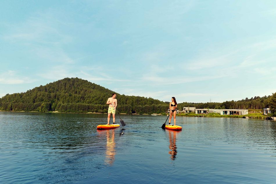 Couple faisant du paddle sur un lac entouré de forêt, activité romantique et sportive en juillet en pleine nature