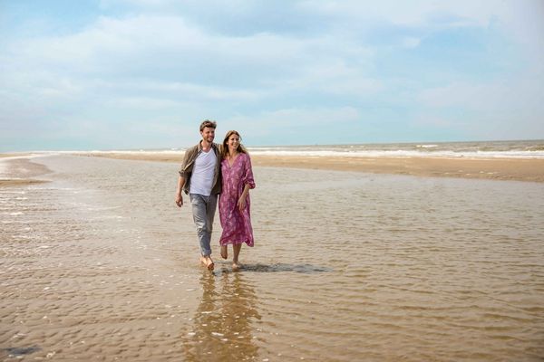 Couple marchant pieds nus sur la plage en bord de mer en Normandie, escapade romantique en juillet