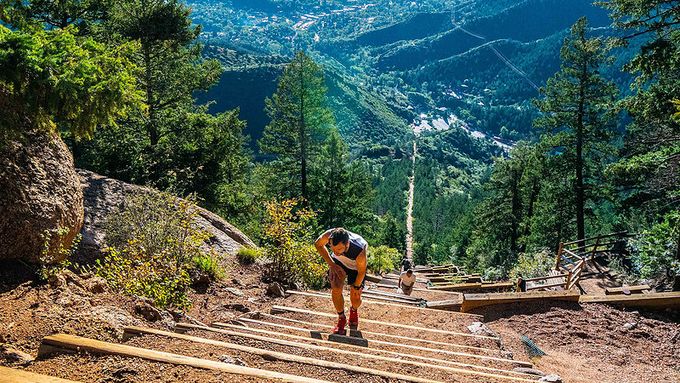 man resting whilst walking up steps surrounded by greenary