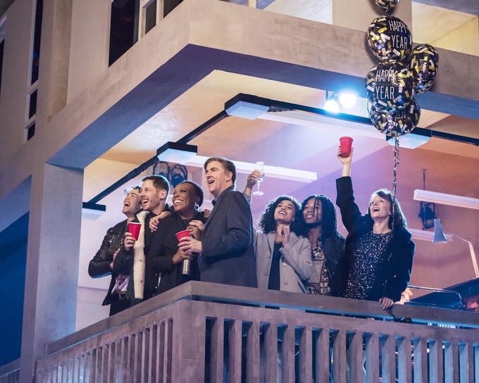 Group of people celebrating looking over balcony with balloons at night