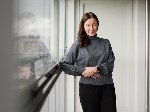 Kuvassa SATOn asuntoliiketoiminnan johtaja Elina Vaurasalo vuokra-asunnon parvekkeella. Elinalla on harmaa paita ja tummanruskeat hiukset. Parvekelasituksen takaa näkyy taloja.